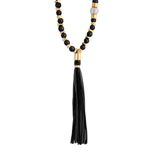Collar de cuentas negras con detalles dorados, una cuenta blanca y un colgante de borla negra, acentuado con detalles metálicos dorados.