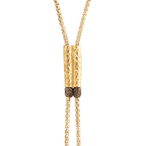 Collar dorado con cadena doble y un cilindro texturizado como pieza central.