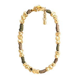 Pulsera de diseño moderno que combina cuentas doradas irregulares con secciones de cuero color taupe y verde olivo. Las cuentas doradas tienen formas únicas y facetadas, dando un aspecto orgánico y artesanal. El cuero color taupe y verde olivo está dispuesto en pequeñas secciones entre grupos de cuentas doradas. La pulsera tiene un cierre circular dorado con un diseño distintivo y grabado con el texto "CORSO". Una pequeña cadena dorada cuelga del cierre, probablemente para ajustar el tamaño. El contraste en