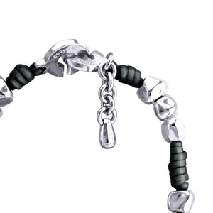 "Cierre de broche de langosta plateado de una pulsera con cuentas plateadas, con un pequeño colgante grabado con la marca 'CORSO' y una cadena de ajuste de eslabones plateados."