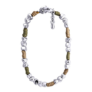 Pulsera de diseño moderno que combina cuentas de plata irregulares con secciones de cuero color taupe y olivo. Las cuentas plateadas tienen formas únicas y facetadas, dando un aspecto orgánico y artesanal. El cuero color taupe y olivo está dispuesto en pequeñas secciones entre grupos de cuentas plateadas. La pulsera tiene un cierre circular plateado con un diseño distintivo. Una pequeña cadena plateada cuelga del cierre, probablemente para ajustar el tamaño. El contraste entre la plata brillante y el cuero 