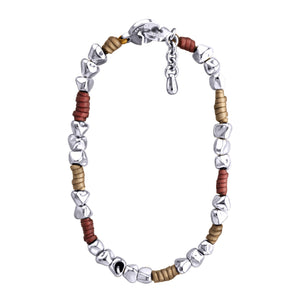 Pulsera de diseño moderno que combina cuentas de plata irregulares con secciones de cuero color taupe y tinto. Las cuentas plateadas tienen formas únicas y facetadas, dando un aspecto orgánico y artesanal. El cuero color taupe y tinto está dispuesto en pequeñas secciones entre grupos de cuentas plateadas. La pulsera tiene un cierre circular plateado con un diseño distintivo. Una pequeña cadena plateada cuelga del cierre, probablemente para ajustar el tamaño. El contraste entre la plata brillante y el cuero 
