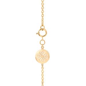 Primer plano de una pulsera de oro de cadena fina, mostrando un cierre de mosquetón circular y un colgante redondo con un delicado diseño calado en forma de corazones entrelazados.
Detalle de un elegante mosquetón circular y un dije redondo con un patrón floral.