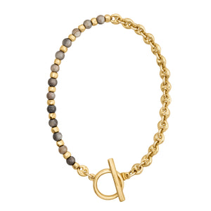 Brazalete con cuentas en tonos grises y dorado, complementado con una cadena dorada y cierre estilo Omega.