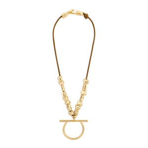 Collar de cordón color brandy con cuentas doradas de forma irregular, con un colgante central en forma de aro y barra horizontal. El collar se cierra con un broche de gancho dorado, complementando el diseño minimalista y elegante.