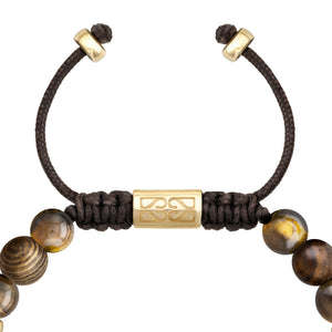 Detalle de cierre ajustable de cordón negro con un cilindro metálico dorado grabado en el centro de la pulsera.