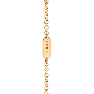 Cadena de oro con placa grabada CORSO. La cadena es delgada y está formada por eslabones circulares. En el centro hay una pequeña placa rectangular de oro con la palabra CORSO grabada en vertical. La placa está integrada en la cadena como parte del diseño.