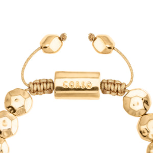 Detalle de pulsera dorada con cuentas brillantes y cierre ajustable de la marca Corso.