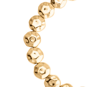 Vista cercana de las cuentas doradas de una pulsera, con un diseño facetado y brillante.